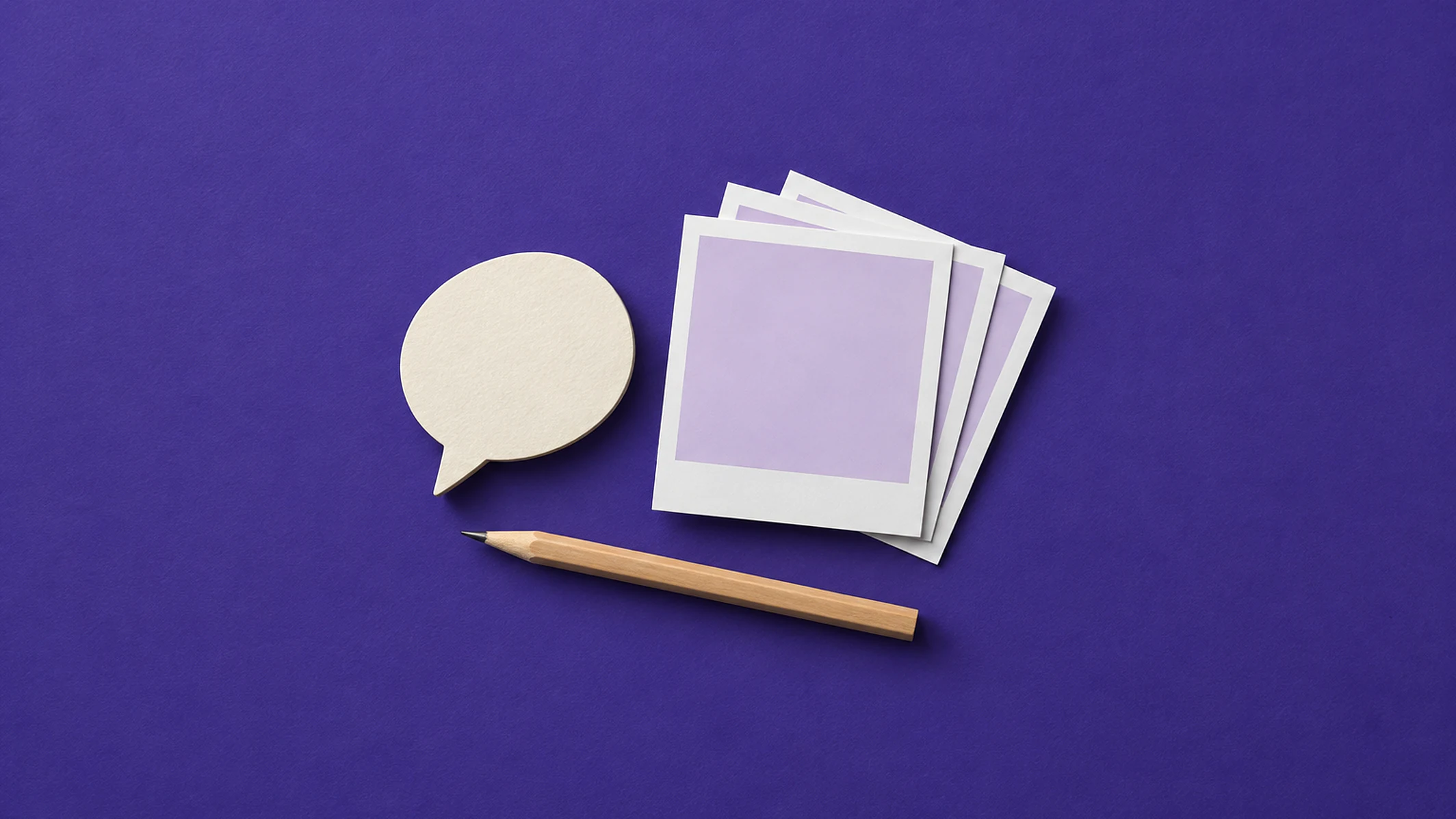 Balão de fala recortado em papel creme ao lado de uma pilha de fotos quadradas em branco e de um lápis, sobre papel violeta